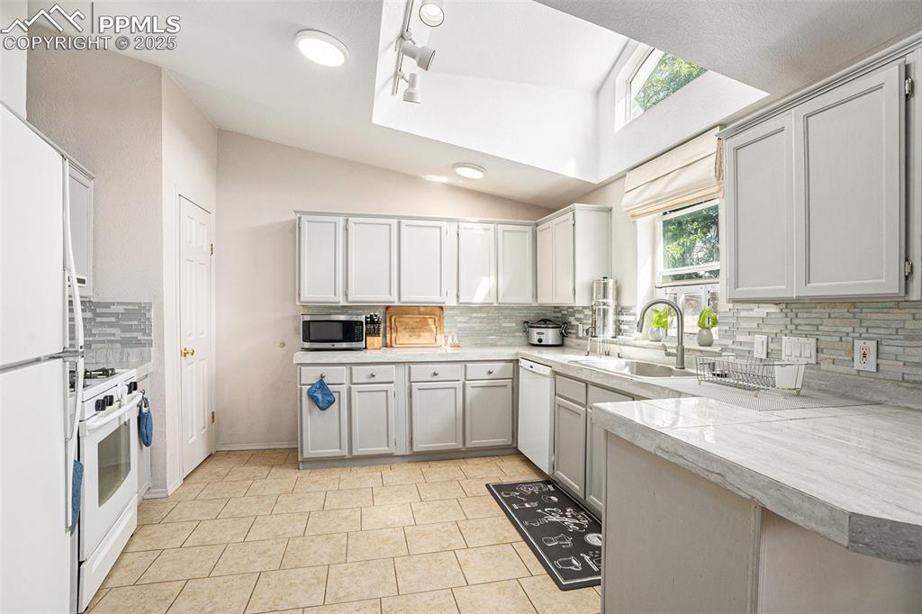Image 10 of 24: Kitchen featuring decorative backsplash, light countertops, white appliance