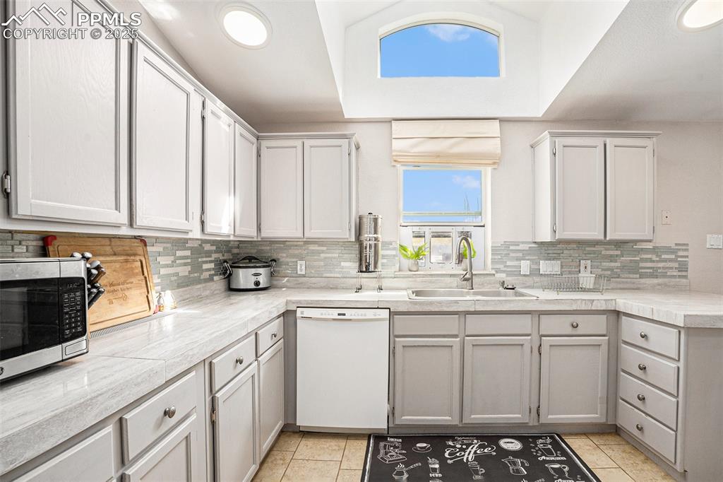 Image 11 of 24: Kitchen with white dishwasher, a peninsula, stainless steel microwave, ligh