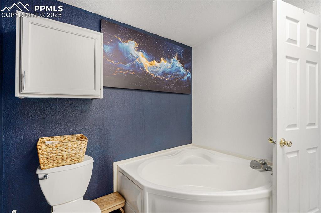Image 15 of 24: Full bathroom featuring a textured wall, a garden tub, and a textured ceili