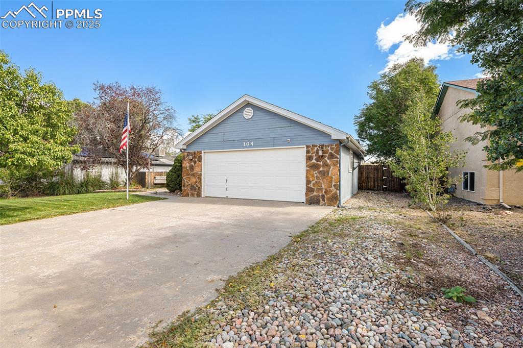 Image 3 of 24: View of property exterior with a garage, stone siding, and concrete drivewa