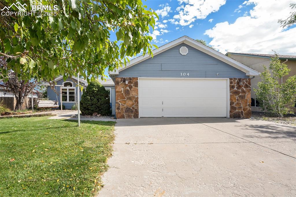 Image 4 of 24: Single story home featuring stone siding, driveway, a front yard, and a gar