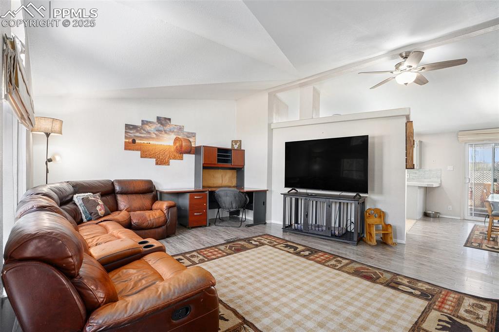 Image 6 of 24: Living area featuring wood finished floors, vaulted ceiling, ceiling fan, a