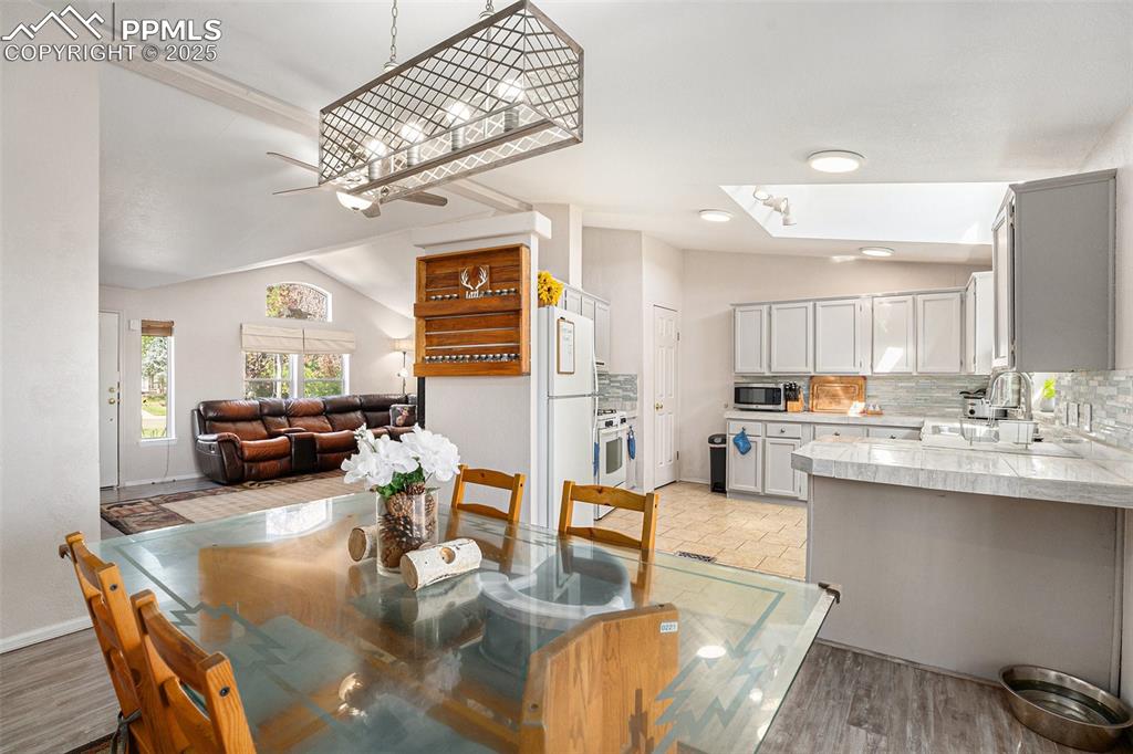 Image 9 of 24: Dining space featuring vaulted ceiling and light wood finished floors