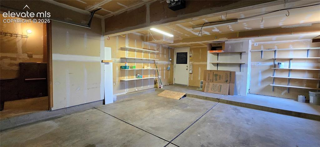 Image 19 of 19: Garage with storage shelves, and laundry nook (insulated)