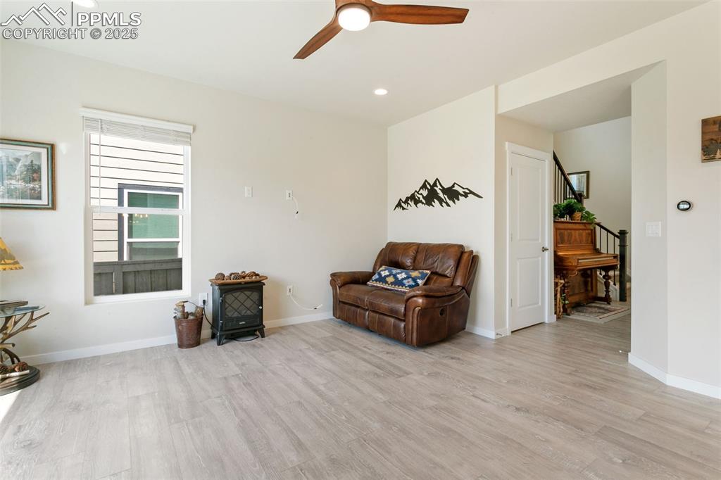 Image 16 of 50: Sitting room featuring a wood stove, recessed lighting, stairs, light wood