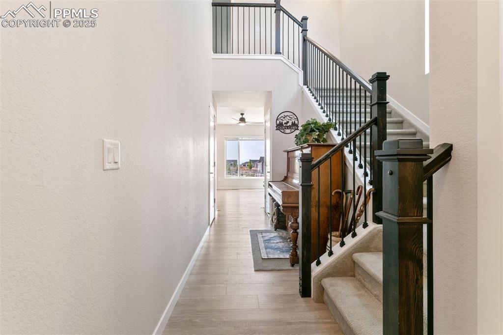 Image 2 of 50: Stairs with wood finished floors, ceiling fan, and a towering ceiling