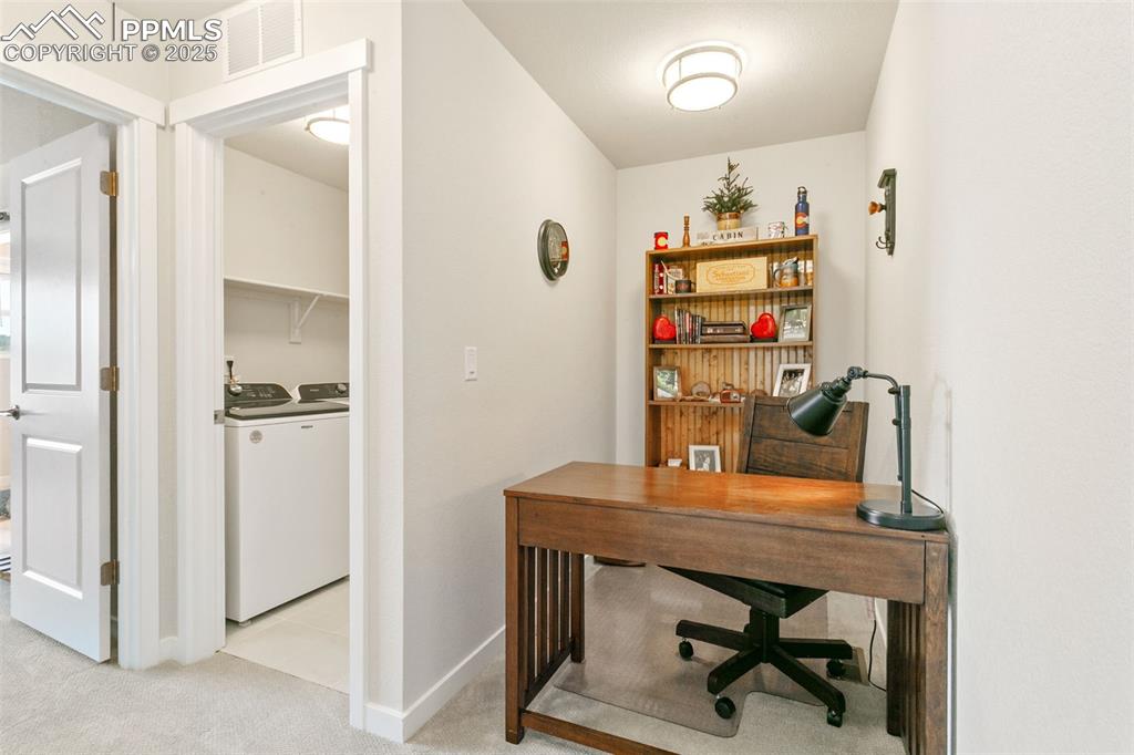 Image 21 of 50: Office space with light carpet and washing machine and clothes dryer