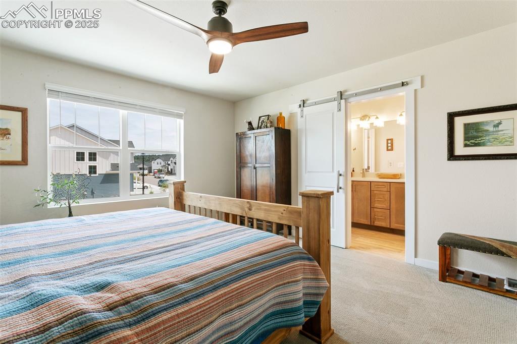 Image 22 of 50: Bedroom featuring light carpet, a barn door, ensuite bathroom, and ceiling