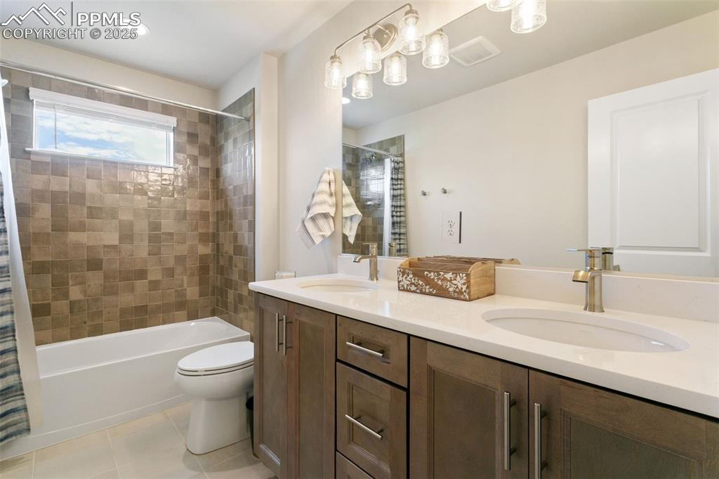 Image 30 of 50: Bathroom featuring double vanity, shower / tub combo with curtain, and tile