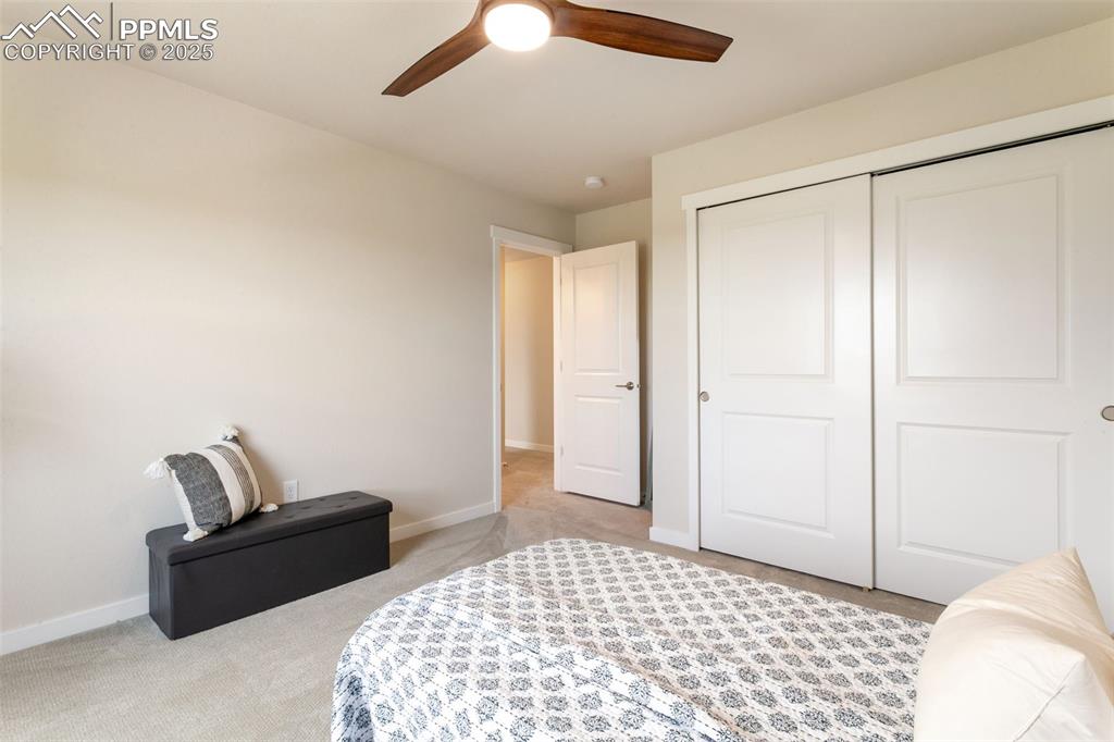 Image 32 of 50: Bedroom with light carpet, a closet, and a ceiling fan