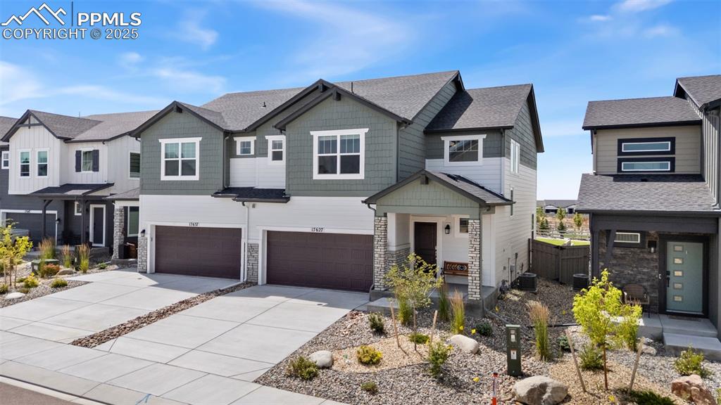 Image 36 of 50: Craftsman-style home with stone siding, an attached garage, driveway, and a
