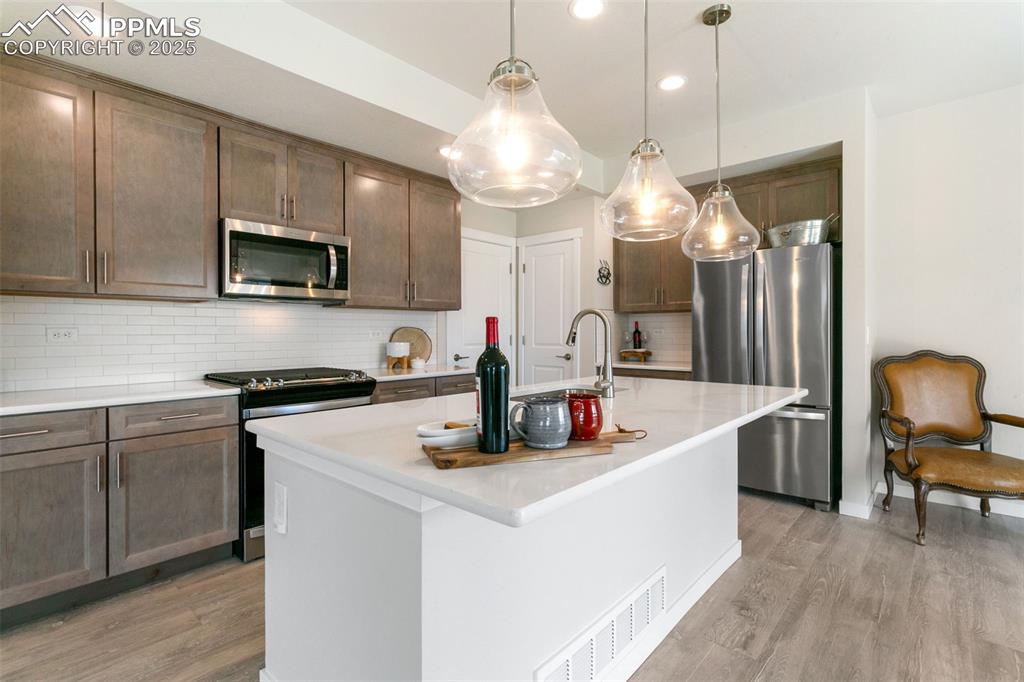 Image 4 of 50: Kitchen with stainless steel appliances, tasteful backsplash, light wood-st