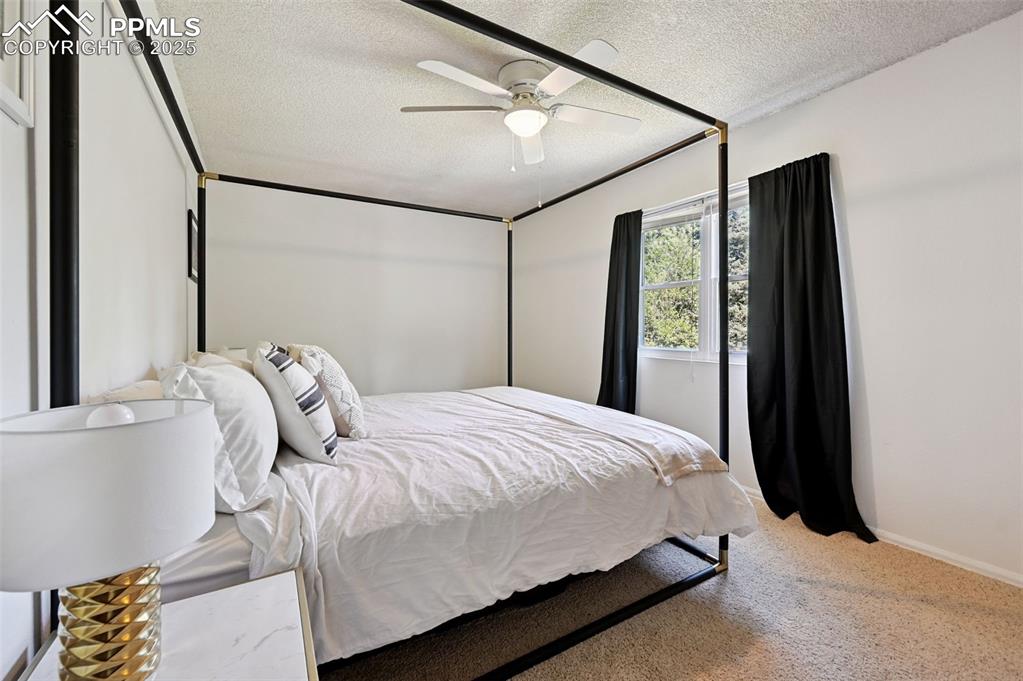 Image 13 of 31: Carpeted bedroom with a textured ceiling and ceiling fan