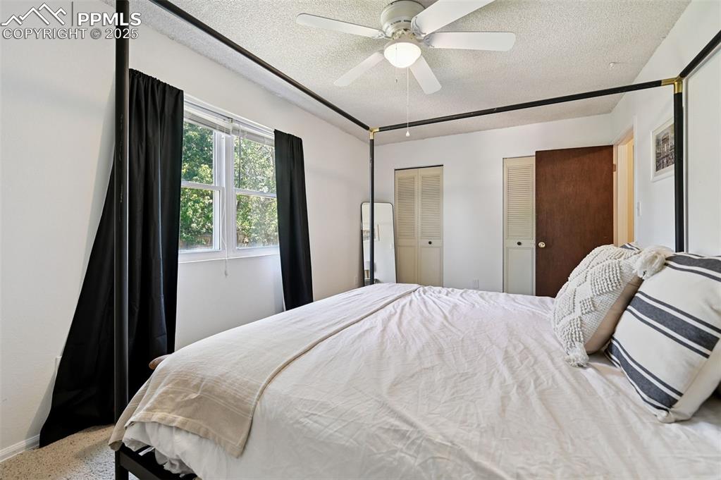 Image 14 of 31: Bedroom featuring a textured ceiling, multiple closets, and a ceiling fan