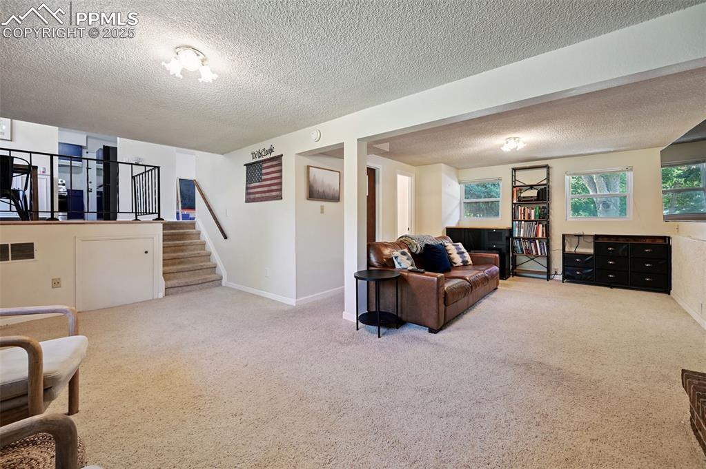 Image 20 of 31: Carpeted living room featuring a textured ceiling and stairs