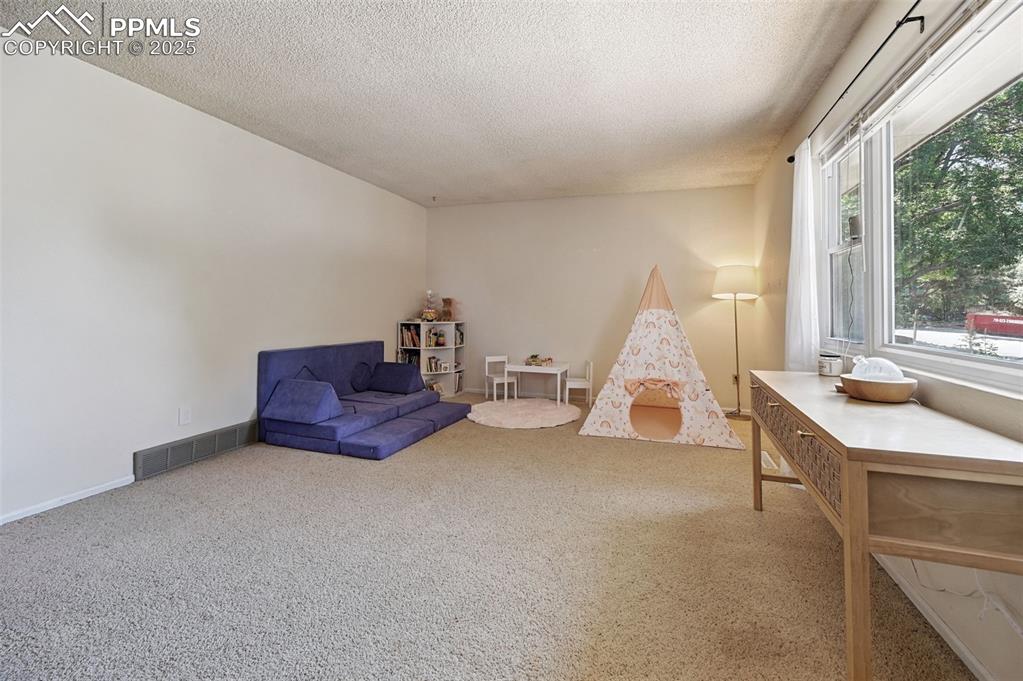Image 5 of 31: Sitting room with a textured ceiling and carpet flooring