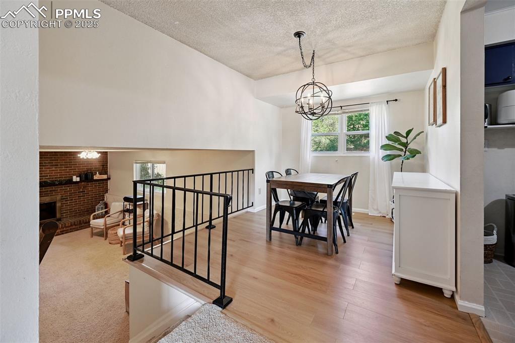 Image 7 of 31: Dining room with a chandelier, a textured ceiling, a fireplace, and light w