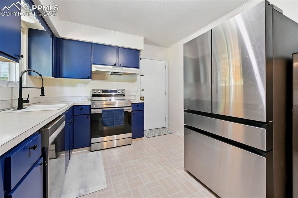 Image 8 of 31: Kitchen with appliances with stainless steel finishes, blue cabinets, under