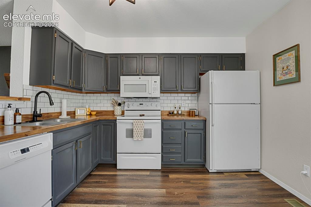 Image 10 of 32: Kitchen with wood-finish flooring, white subway tile backsplash, dark cabin