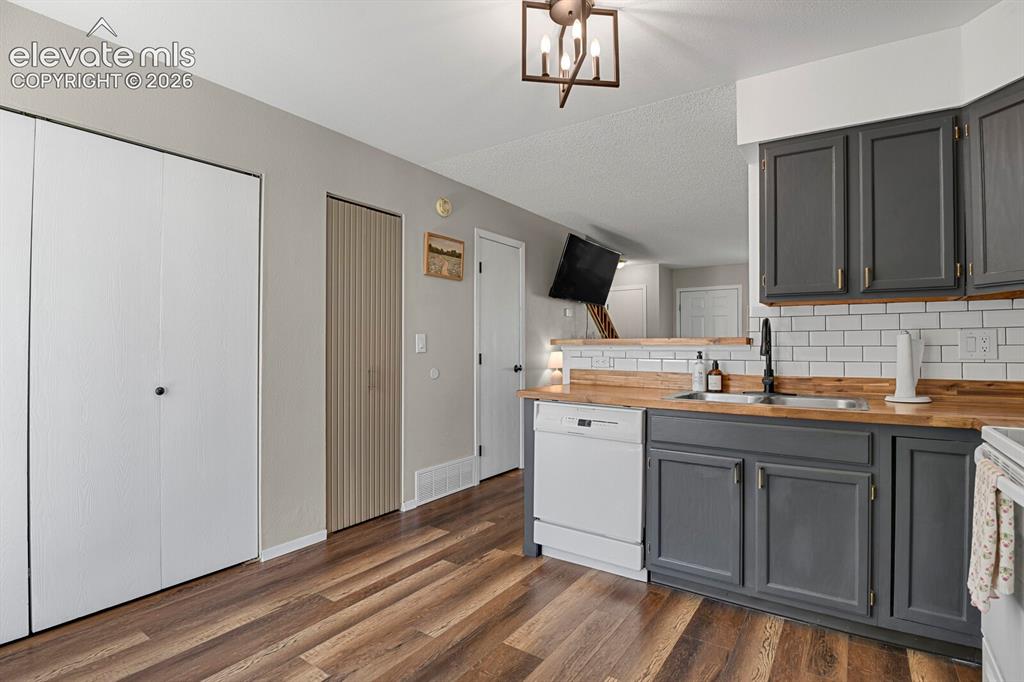 Image 11 of 32: Kitchen featuring dark gray cabinetry, wood-finish countertops, subway tile