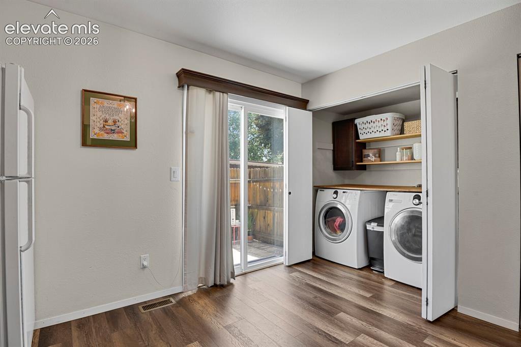 Image 13 of 32: Wood-finish flooring with a dedicated laundry area featuring built-in shelv