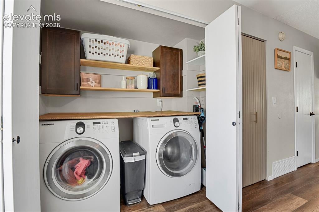 Image 14 of 32: Laundry area featuring wood-finish flooring, two front-loading appliances,