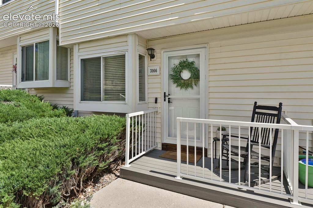 Image 3 of 32: Entry porch with white railing, vinyl siding, bay windows, and exterior lig