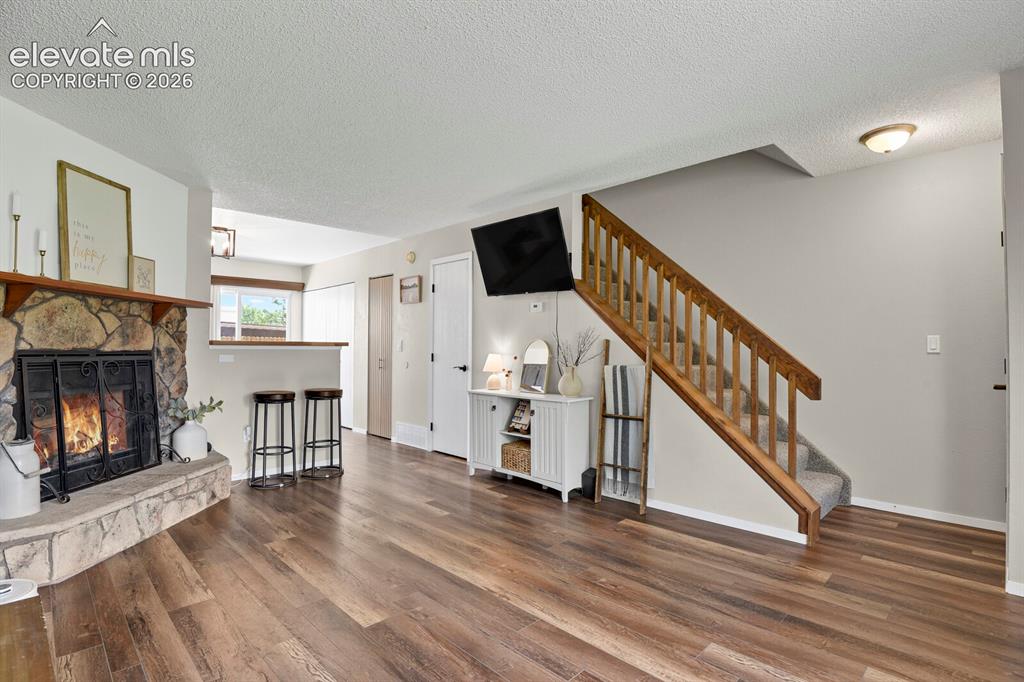 Image 7 of 32: Stone-clad fireplace with a wood mantle, wood-finish flooring, a built-in b