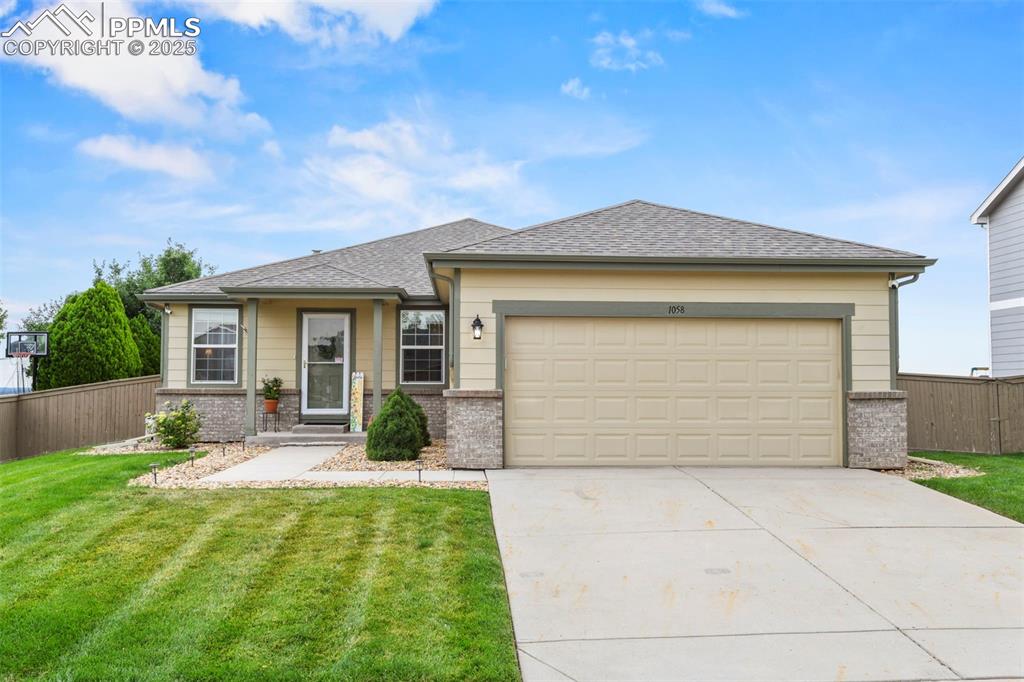 Caption: View of front of home featuring brick siding, a shingled roof, driveway, and an attached garage
