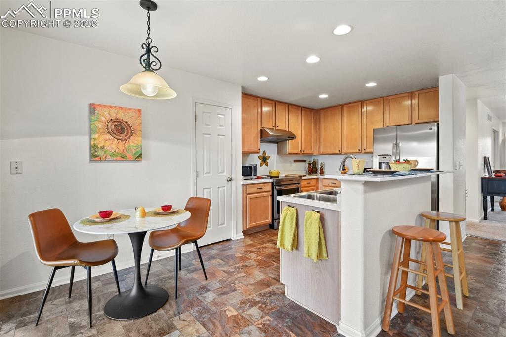 Image 12 of 32: Kitchen featuring recessed lighting, light countertops, hanging light fixtu