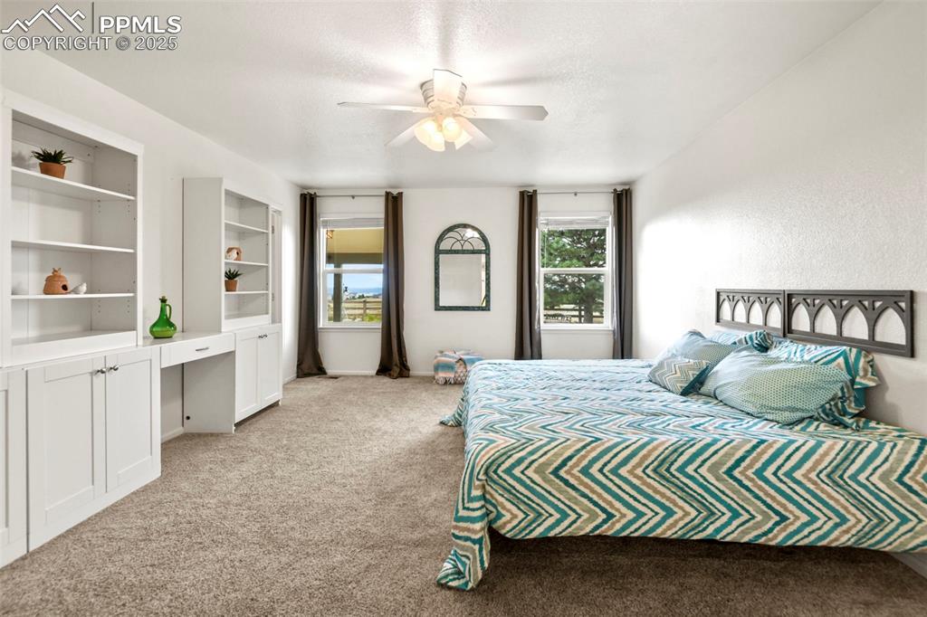Image 15 of 32: Bedroom with light carpet, a ceiling fan, and a textured ceiling