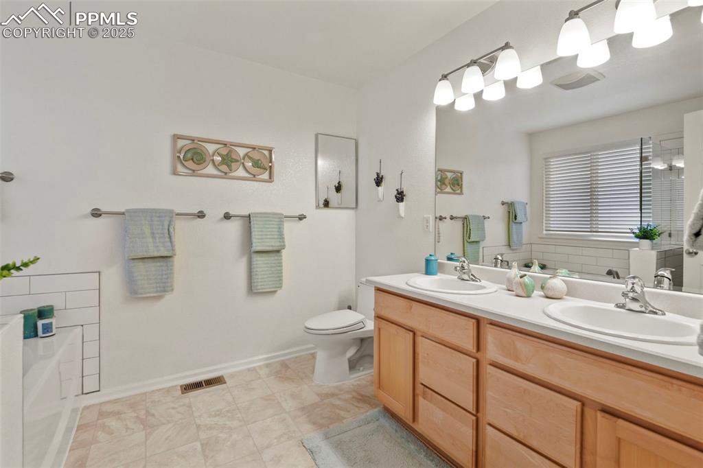 Image 17 of 32: Full bath with a bath, double vanity, and light tile patterned floors