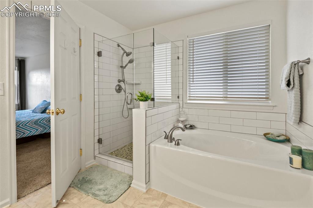 Image 18 of 32: Ensuite bathroom featuring a bath, a shower stall, and light tile patterned