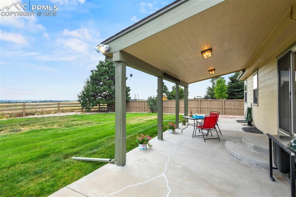 Image 25 of 32: Fenced backyard with a patio area and outdoor dining area