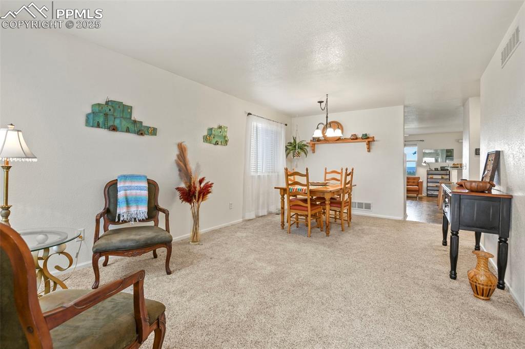 Image 5 of 32: Dining space with light colored carpet and a textured ceiling