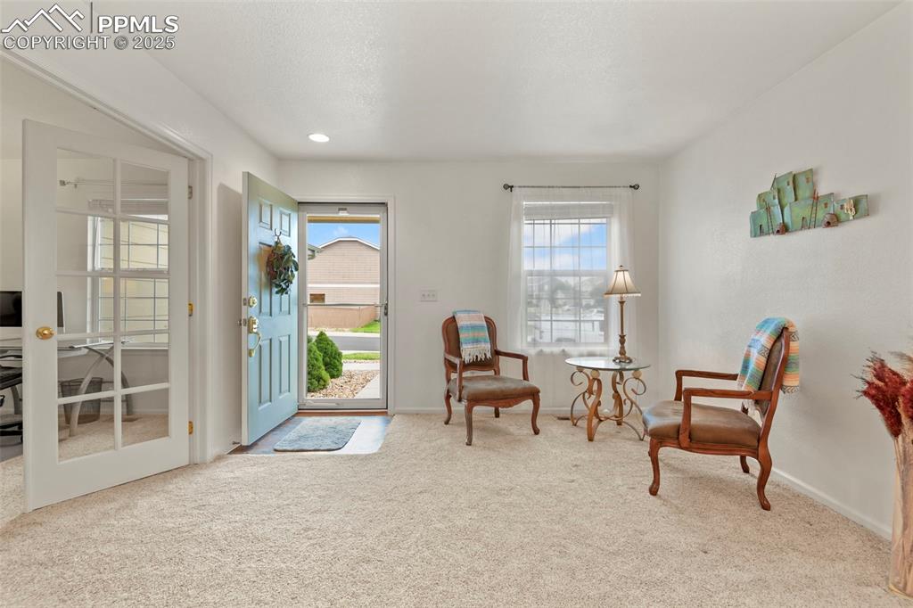 Image 6 of 32: Sitting room with light colored carpet and a desk