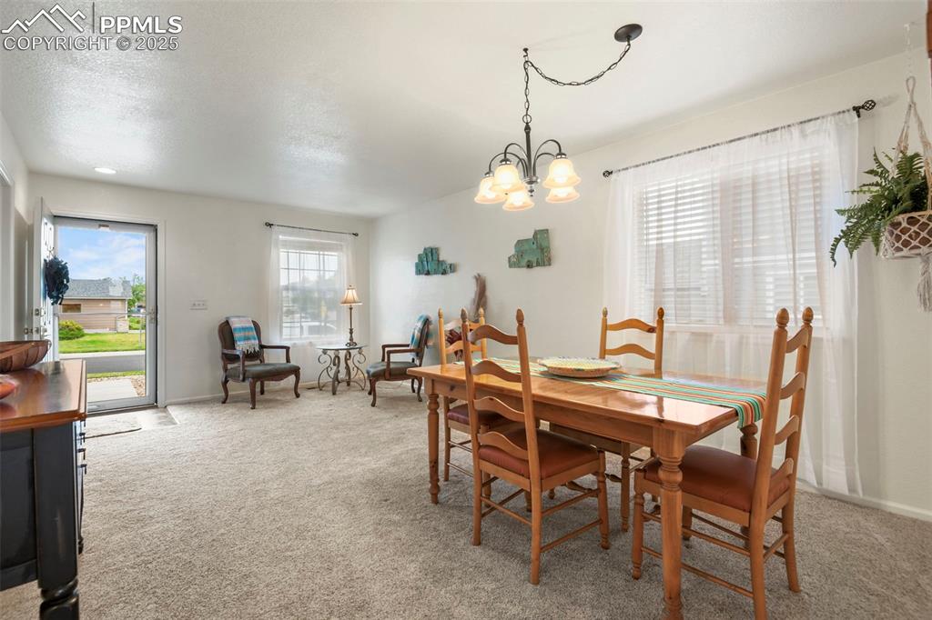 Image 7 of 32: Dining space with light carpet, a chandelier, and a textured ceiling