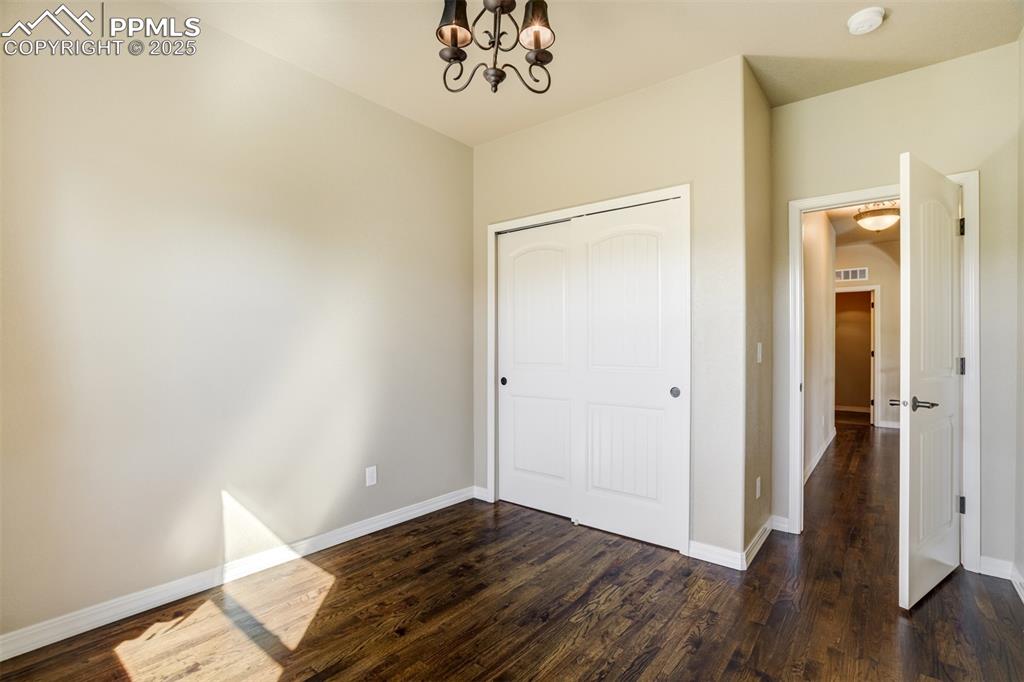 Image 18 of 36: Unfurnished bedroom with a chandelier, dark wood-type flooring, and a close