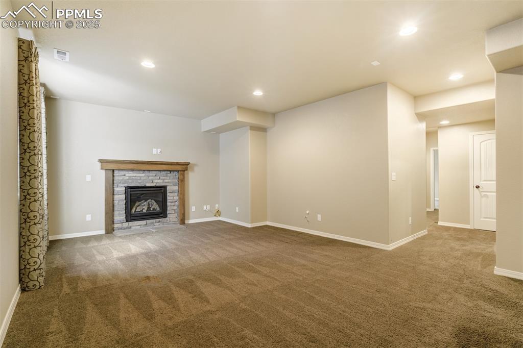 Image 20 of 36: Unfurnished living room with carpet flooring, a glass covered fireplace, an