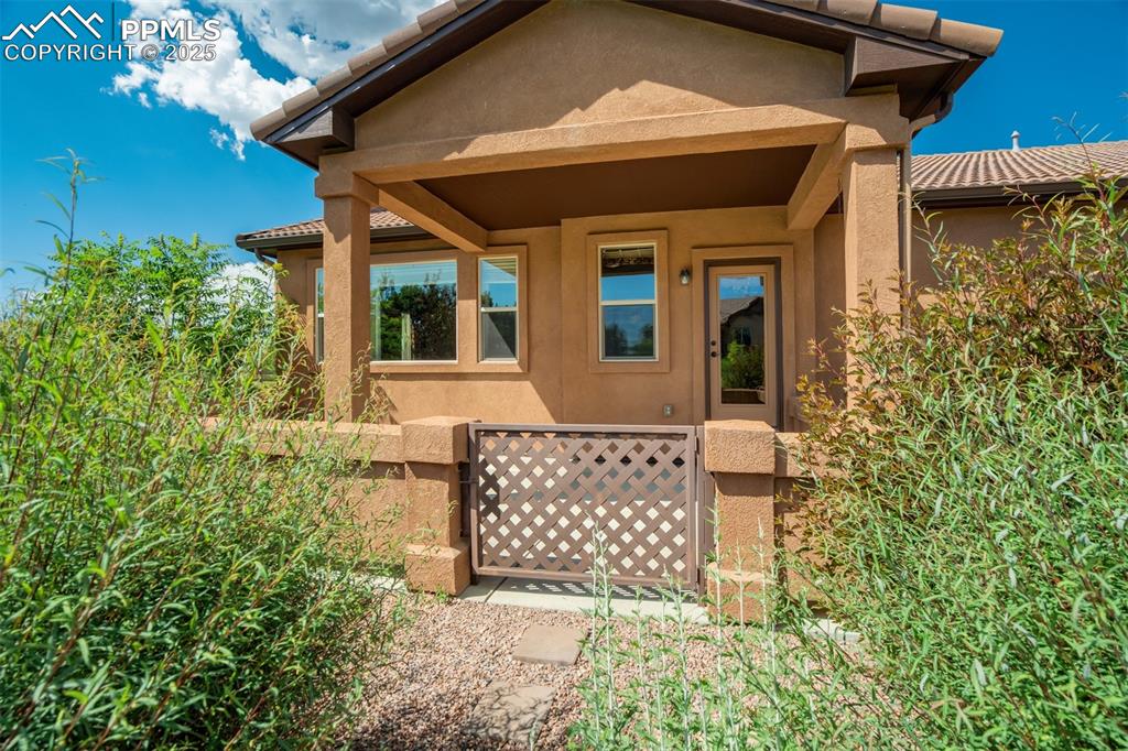 Image 29 of 36: View of exterior entry with stucco siding and a tiled roof