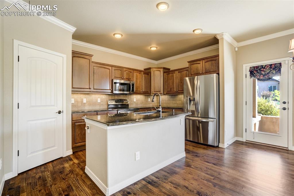 Image 7 of 36: Kitchen featuring appliances with stainless steel finishes, dark wood finis