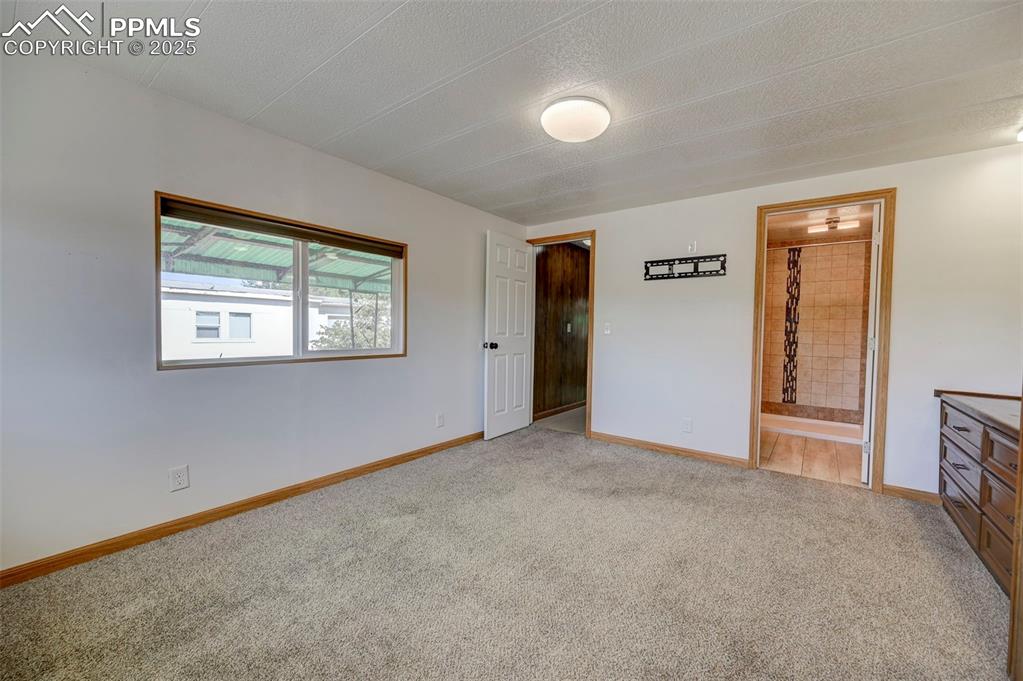 Image 12 of 26: Unfurnished bedroom with light carpet, a textured ceiling, and ensuite bath