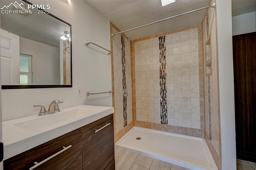 Image 13 of 26: Full bath featuring vanity, a stall shower, and a textured ceiling