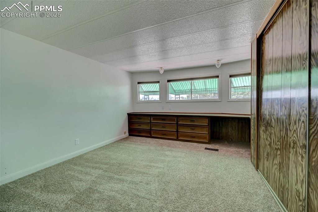 Image 14 of 26: Carpeted spare room featuring built in study area and baseboards