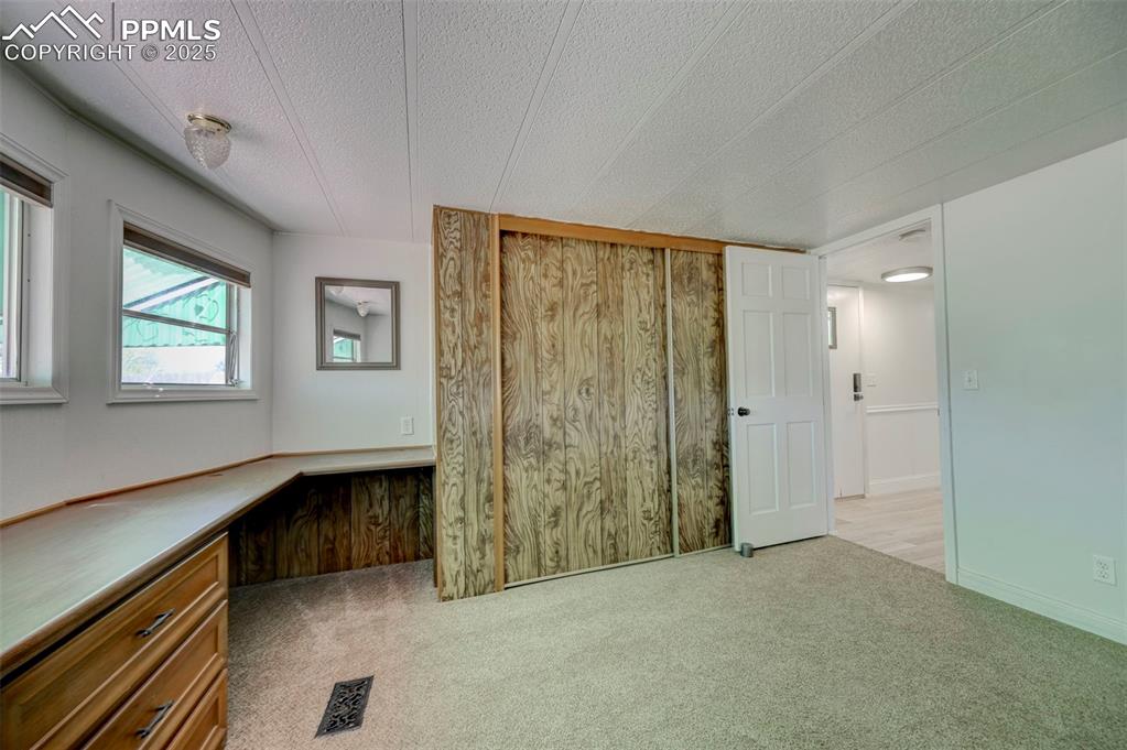 Image 15 of 26: Unfurnished bedroom with carpet flooring, a textured ceiling, and wooden wa