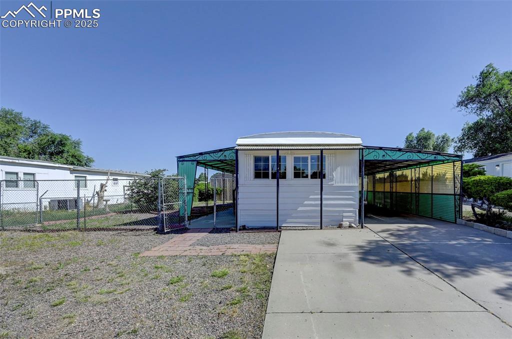 Image 18 of 26: View of outbuilding featuring concrete driveway and a carport