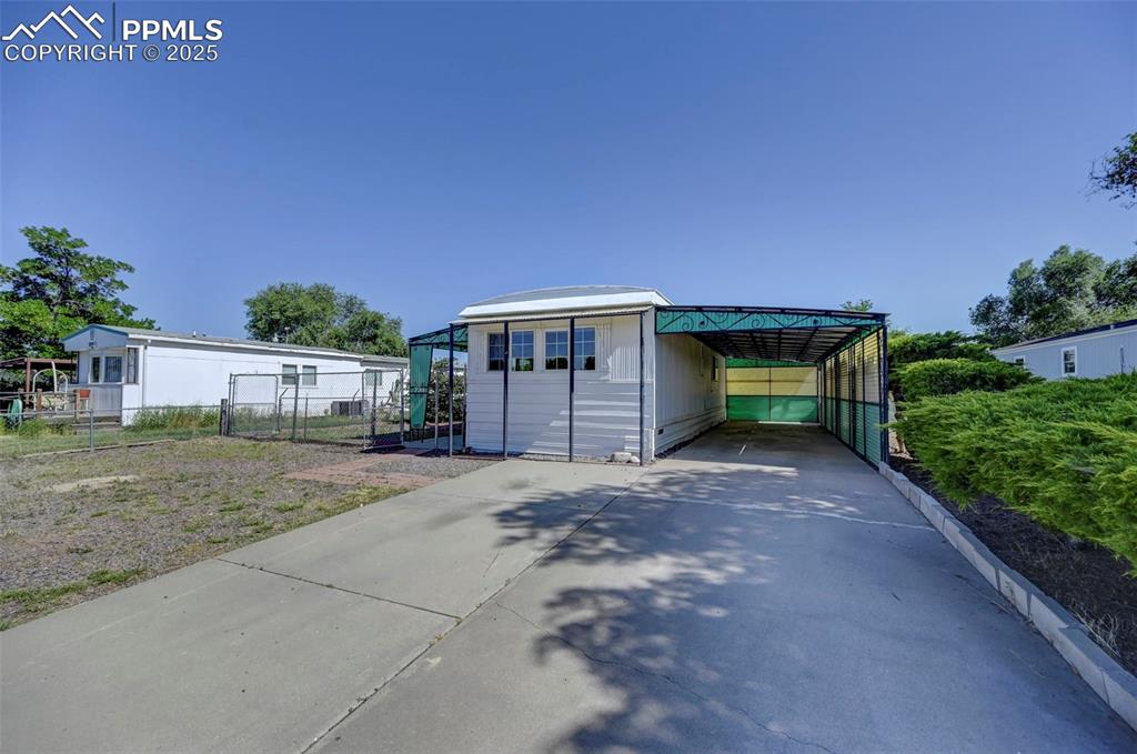 Image 19 of 26: View of outdoor structure featuring concrete driveway and a carport