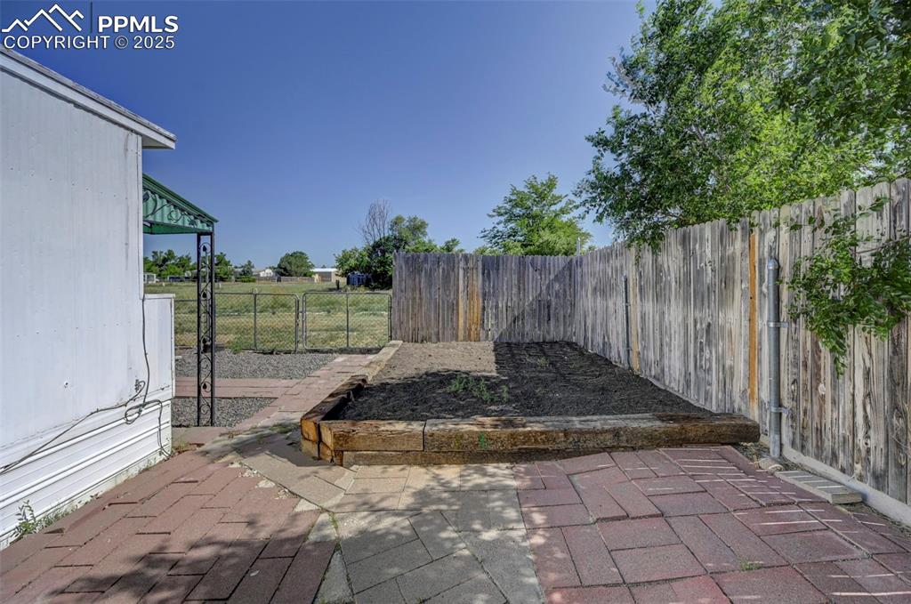 Image 22 of 26: Fenced backyard with a patio area