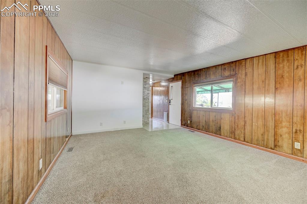 Image 5 of 26: Carpeted spare room featuring wooden walls and baseboards