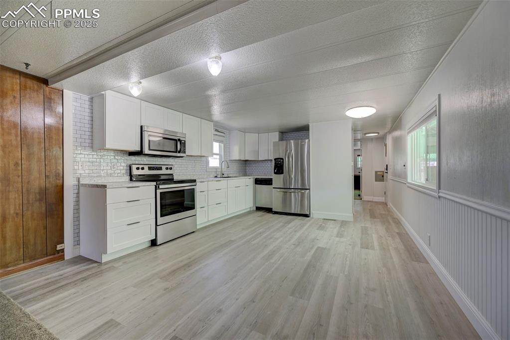 Image 7 of 26: Kitchen with appliances with stainless steel finishes, light countertops, l